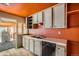 A view of a kitchen with outdated cabinets and appliances. The walls are orange and the floor is a worn hardwood at 1645 Little Bear Creek Rd, Idaho Springs, CO 80452