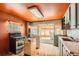 A different view of the kitchen with an orange wall with an outdated oven, and hardwood floors at 1645 Little Bear Creek Rd, Idaho Springs, CO 80452