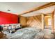 Open living room area with red accent wall, wood beam, and unique wooden wall design at 1645 Little Bear Creek Rd, Idaho Springs, CO 80452