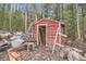 Exterior view of a red shed, surrounded by wood, tires, and other debris at 1645 Little Bear Creek Rd, Idaho Springs, CO 80452