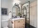 Modern bathroom with wood-look vanity, glass enclosed shower with black accents, and hexagon tiled floor at 4712 S Wabash St, Denver, CO 80237