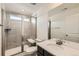 Modern bathroom featuring tiled walk-in shower with glass doors, neutral tile, and a single vanity at 17632 Datura St, Broomfield, CO 80023