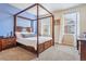 Primary bedroom featuring a wooden canopy bed, light-colored walls, and large windows, creating a serene retreat at 6284 Orion Ct # B, Arvada, CO 80403
