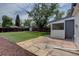 Large backyard featuring a lush lawn, stone patio, mature tree and storage shed at 2812 Krameria St, Denver, CO 80207