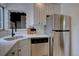 Compact kitchen with stainless steel appliances, white cabinets, and quartz countertops at 2812 Krameria St, Denver, CO 80207