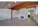 Open-concept living room with fireplace, painted brick wall, wood floors and beamed ceiling at 2812 Krameria St, Denver, CO 80207