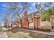 A sunny townhouse exterior shows brown siding, a brick chimney, covered porches and neat landscaping at 2062 S Helena St # B, Aurora, CO 80013