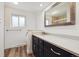 Modern bathroom with dark wood cabinets, wood-look floors and a wide mirror at 6609 W Mexico Pl, Lakewood, CO 80232