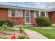 Close up of the brick exterior and front yard featuring lush greenery and a garden bench at 6609 W Mexico Pl, Lakewood, CO 80232