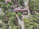 An aerial shot exhibits the home surrounded by a lush green forest and driveway at 17720 Canterbury Dr, Monument, CO 80132