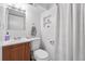 A well-lit bathroom featuring a wood vanity, toilet, and shower with a curtain at 3008 N York St, Denver, CO 80205