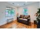 Bright living room featuring hardwood floors, white walls, and a comfortable brown leather couch at 530 S Ames St, Lakewood, CO 80226