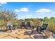 Serene stone patio with rustic wood chairs, surrounded by lush greenery and a clear blue sky at 6999 S Tempe Ct, Aurora, CO 80016