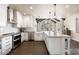 Bright kitchen with white cabinets, stainless steel appliances, island and countertops with sink and elegant pendant lighting at 7099 Cerney Cir, Castle Pines, CO 80108