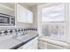 Kitchen with white cabinets, large window, a double sink and black and white tiled backsplash at 1475 N Humboldt St # 22, Denver, CO 80218