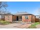 Exterior view of brick home, showcasing its neat front lawn, driveway, and cozy front porch seating area at 4563 W 34Th Ave, Denver, CO 80212