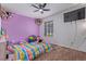 Colorful bedroom with a ceiling fan, rainbow bedding, and purple accent wall at 7925 York St # 2, Denver, CO 80229