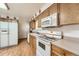 Functional kitchen with wooden cabinets, white appliances, and laminate flooring at 678 S Oswego Ct, Aurora, CO 80012