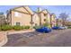 Exterior view of condo building with light brown siding and green landscaping, showing the available parking at 9390 W Chatfield Pl # 104, Littleton, CO 80128