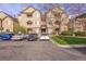 A condo building with light brown siding, stone accents, covered parking, and well-maintained landscaping at 9390 W Chatfield Pl # 104, Littleton, CO 80128