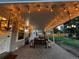 Covered backyard patio with brick pavers and string lights at twilight at 6953 S Prescott St, Littleton, CO 80120