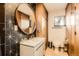 Bathroom features eye-catching geometric tile walls, modern vanity and fixtures, and a round mirror at 9309 Highland Pl, Arvada, CO 80002