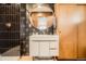 Bathroom showcases black and white star tile walls, wood door, a modern vanity, and round mirror at 9309 Highland Pl, Arvada, CO 80002