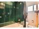 Bathroom shower with a shower-tub, modern green tile, gold fixtures, and a showerhead at 9309 Highland Pl, Arvada, CO 80002