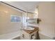 Compact bathroom featuring white tiled walls and a shower-tub combo with a single sink vanity at 310 Jay St, Lakewood, CO 80226