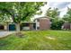 This house features a charming exterior with a brick facade, lawn, mature trees, and attached garage at 3111 Troy St, Aurora, CO 80011