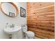 Half bath with a wood accent wall, a unique mirror, and a pedestal sink at 6046 Gilbert Way, Golden, CO 80403
