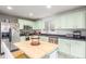 Modern kitchen showcasing stainless appliances, a butcher block island, and light green cabinetry at 6193 Brantly Ave, Castle Rock, CO 80104