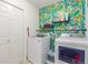 Well-equipped laundry room with a washer, dryer, patterned wallpaper, and storage shelves at 6193 Brantly Ave, Castle Rock, CO 80104