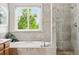Bright bathroom with a soaking tub under a window and tiled shower with glass door at 1205 W 11Th Ct, Broomfield, CO 80020