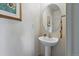Charming powder room featuring a pedestal sink, round mirror, and elegant decorative accents at 1205 W 11Th Ct, Broomfield, CO 80020