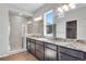 Elegant bathroom featuring double vanities, granite countertops, and a glass-enclosed shower at 10661 Reunion Pkwy, Commerce City, CO 80022