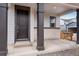 Covered front porch with dark wood pillars and a modern front door at 10661 Reunion Pkwy, Commerce City, CO 80022