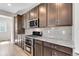 Kitchen features granite countertop, backsplash, stainless steel range, and dark brown cabinetry at 10661 Reunion Pkwy, Commerce City, CO 80022