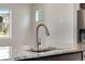 Close-up of kitchen island, featuring granite countertop, stainless steel faucet, and cabinetry at 10661 Reunion Pkwy, Commerce City, CO 80022