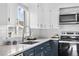 Bright kitchen showcasing navy-blue lower cabinets, white subway tile backsplash, granite countertops, and stainless-steel appliances at 1182 S Alcott St, Denver, CO 80219