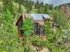 Stunning exterior view of a multi-story home featuring solar panels nestled among tall trees and greenery at 1575 York Gulch Rd, Idaho Springs, CO 80452
