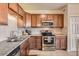 Close-up of kitchen with stainless steel oven, granite counters, and brown cabinets for a modern look at 7292 S Blackhawk St # 2-204, Englewood, CO 80112