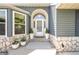 Cozy front porch features a white door with sidelights and stone accents with decorative plants and pots at 995 Chase St, Lakewood, CO 80214