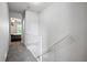 Bright hallway leading to bedroom, featuring neutral paint, carpeted floors, and white railing along the stairs at 2291 S Jasper Way # B, Aurora, CO 80013