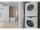 A modern laundry room with stacked washer and dryer units next to a bathroom with a glass shower at 4200 W 17Th Ave # 621, Denver, CO 80204