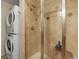 Modern tiled bathroom with a glass door shower and stacked washer and dryer at 3401 S Glencoe St, Denver, CO 80222