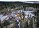 Aerial view of modern home with a large driveway surrounded by trees and snow-covered landscape at 11505 Conifer Ridge Dr, Conifer, CO 80433
