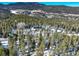 Aerial view of secluded contemporary home surrounded by dense forest and snow-dusted landscape at 11505 Conifer Ridge Dr, Conifer, CO 80433
