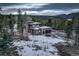 Aerial view of modern home surrounded by trees and snow, featuring a garage and mountain views at 11505 Conifer Ridge Dr, Conifer, CO 80433