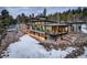 Expansive home featuring multi-level terraces, stone accents, and walls of windows showcasing amazing views at 11505 Conifer Ridge Dr, Conifer, CO 80433
